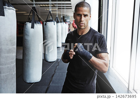 Portrait, punching bag and man in gym for MMA workout, challenge or competition training. Power, muscle and strong champion boxer in exercise with confidence, fitness and energy in boxing sports club Portrait, punching bag and man in gym for MMA workout, challenge or competition training. Power, muscle and strong champion boxer in exercise with confidence, fitness and energy in boxing sports club 142673695