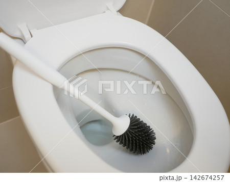 White toilet bowl with a toilet brush in a clean modern bathroom, representing household cleaning, hygiene, sanitation, restroom maintenance and everyday home care. White toilet bowl with a toilet brush in a clean modern bathroom, representing household cleaning, hygiene, sanitation, restroom maintenance and everyday home care. 142674257