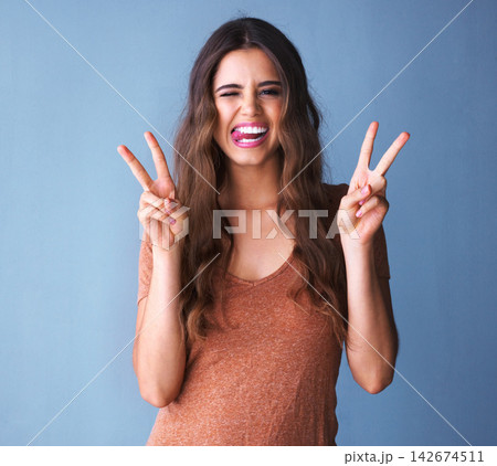 Woman, peace sign and happy in studio portrait with funny face, tongue and fashion by background. Girl, person and model with style, clothes or streetwear with icon, symbol or emoji with comic smile Woman, peace sign and happy in studio portrait with funny face, tongue and fashion by background. Girl, person and model with style, clothes or streetwear with icon, symbol or emoji with comic smile 142674511