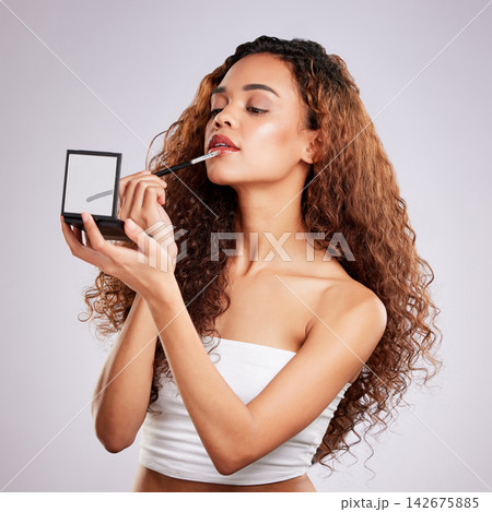 Woman, lipstick and studio with mirror, cosmetic or beauty on gray background. Cosmetology, face or skincare for facial treatment with tool, product or lip application with colour for shine aesthetic Woman, lipstick and studio with mirror, cosmetic or beauty on gray background. Cosmetology, face or skincare for facial treatment with tool, product or lip application with colour for shine aesthetic 142675885