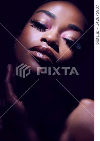 Beauty, face and glamour with black woman in makeup on dark background for cosmetics or elegance. Eyeshadow, lipstick and mascara with bold model person in studio for african pride or art deco Beauty, face and glamour with black woman in makeup on dark background for cosmetics or elegance. Eyeshadow, lipstick and mascara with bold model person in studio for african pride or art deco 142675907
