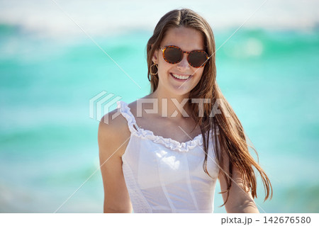 Beach, woman and sunglasses for walk while happy on vacation, holiday and journey in California. Female traveler, ocean and nature for peace, relaxing and enjoying summer trip with confident girl 142676580