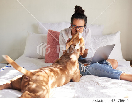 Woman, dog and kiss in a bedroom with remote work, laptop and bonding of rescue animal in a house. Pet, happy and freelancer with foster puppy together in home with calm and relax with computer 142676604
