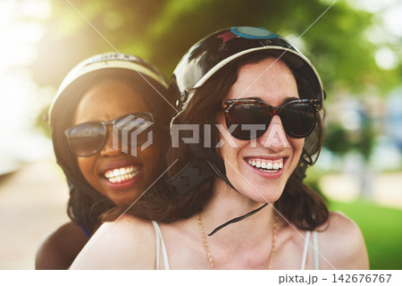Smile, female couple and motor scooter outside with laugh for fun in summer on holiday or vacation. Lesbian, lgbtq and diverse with women in nature or tourist in London park with closeup in sunshine. Smile, female couple and motor scooter outside with laugh for fun in summer on holiday or vacation. Lesbian, lgbtq and diverse with women in nature or tourist in London park with closeup in sunshine. 142676767