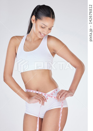 Woman, measuring tape and stomach in studio for progress, tracking weight loss and white background. Female person, check belly and results of liposuction on tummy, cosmetic change and transformation Woman, measuring tape and stomach in studio for progress, tracking weight loss and white background. Female person, check belly and results of liposuction on tummy, cosmetic change and transformation 142676812