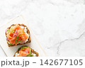 Salmon toast with cream cheese, red onion and arugula on whole grain bread, top view 142677105