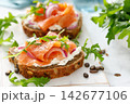 Salmon toast with cream cheese, red onion and arugula on whole grain bread 142677106