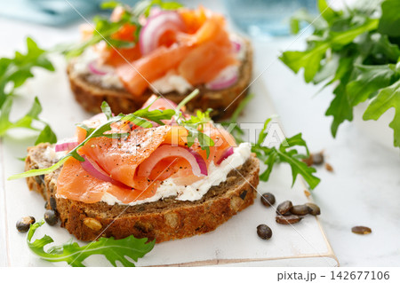 Salmon toast with cream cheese, red onion and arugula on whole grain bread Salmon toast with cream cheese, red onion and arugula on whole grain bread 142677106