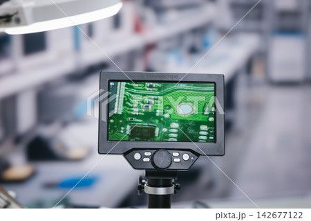 Digital microscope screen a close view of a green circuit board in a modern electronics repair lab. Digital microscope screen a close view of a green circuit board in a modern electronics repair lab. 142677122