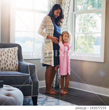 Pregnancy, woman and daughter with listening to stomach for baby kick, excited for newborn and curious with smile in home. Mother, pregnant and happy child with ear on tummy for bonding, care or love 142677234