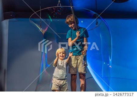 Young boys use hands-on exhibits with water and giant bubbles, showing STEM learning, curiosity and playful science education concept Young boys use hands-on exhibits with water and giant bubbles, showing STEM learning, curiosity and playful science education concept 142677317