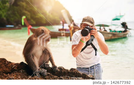 Man, camera and monkey with holiday, beach and tropical island with getaway trip, Bali and tourism. Person, photographer and tourist with equipment, seaside and memory with wild animal and sunshine Man, camera and monkey with holiday, beach and tropical island with getaway trip, Bali and tourism. Person, photographer and tourist with equipment, seaside and memory with wild animal and sunshine 142677392