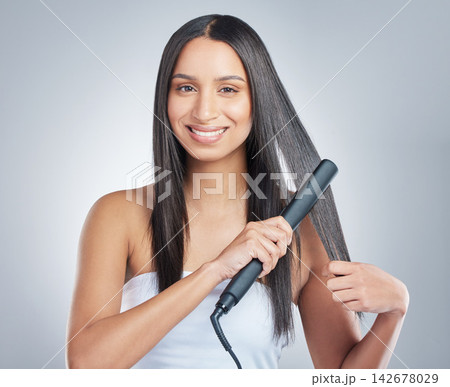 Portrait, beauty and happy woman with hair straightener in studio for style, treatment and shampoo shine results on grey background. Haircare, flat iron and model face with smooth, texture or growth Portrait, beauty and happy woman with hair straightener in studio for style, treatment and shampoo shine results on grey background. Haircare, flat iron and model face with smooth, texture or growth 142678029