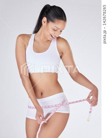 Waist, healthy or woman with tape measure for fitness, body growth or workout in studio on white background. Girl model, progress or happy athlete with stomach exercise or training to lose weight Waist, healthy or woman with tape measure for fitness, body growth or workout in studio on white background. Girl model, progress or happy athlete with stomach exercise or training to lose weight 142678265
