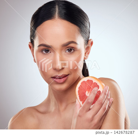 Beauty, diet and grapefruit with portrait of woman in studio on white background for wellness. Aesthetic, fruit and nutrition with face of serious model at spa for cosmetics, dermatology or skincare Beauty, diet and grapefruit with portrait of woman in studio on white background for wellness. Aesthetic, fruit and nutrition with face of serious model at spa for cosmetics, dermatology or skincare 142678287