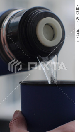 Vertical video. A woman pours herbal tea from a thermos, close-up. Vertical video. A woman pours herbal tea from a thermos, close-up. 142680308