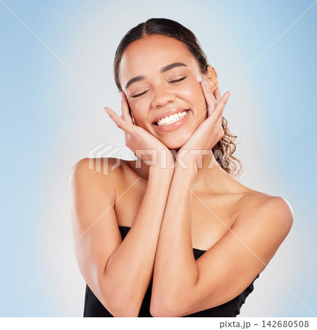 Makeup, skincare and beauty of happy woman in studio for glow, shine or health isolated on blue background. Face, touch and smile of model in cosmetics for dermatology or wellness with eyes closed Makeup, skincare and beauty of happy woman in studio for glow, shine or health isolated on blue background. Face, touch and smile of model in cosmetics for dermatology or wellness with eyes closed 142680508