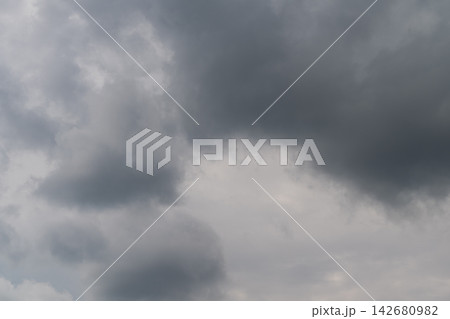 Brooding clouds gather over a serene landscape hinting at an impending storm in the late afternoon sky 142680982