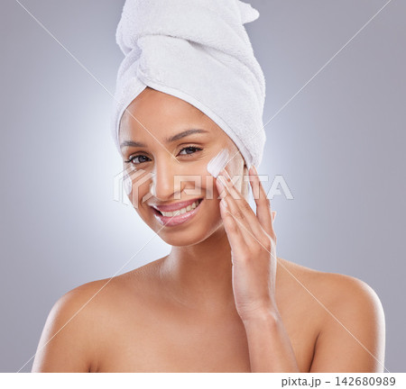 Studio, woman and towel for cream or cosmetics, moisturizer and hand on white background. Skincare, dermatology and beauty for female person, smile or portrait for lotion with glow or product on face Studio, woman and towel for cream or cosmetics, moisturizer and hand on white background. Skincare, dermatology and beauty for female person, smile or portrait for lotion with glow or product on face 142680989