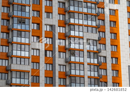 Modern architecture shines with vibrant orange accents on a city high-rise building reflecting the blue sky Modern architecture shines with vibrant orange accents on a city high-rise building reflecting the blue sky 142681852