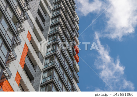 Unique modern building reaching towards the bright blue sky embellished with white clouds on a sunny day 142681866