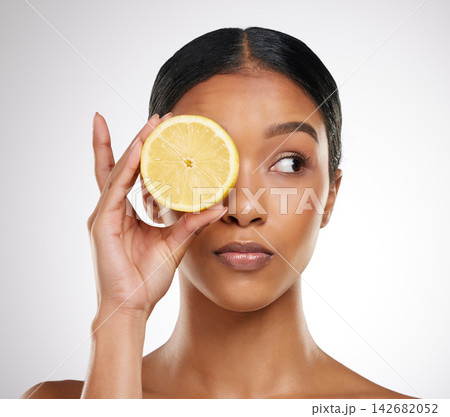 Skincare, face or woman with lemon eye in studio for wellness, glow and organic dermatology on white background. Fruit, beauty or model with sustainable citrus cosmetic, vegan or eco friendly product 142682052