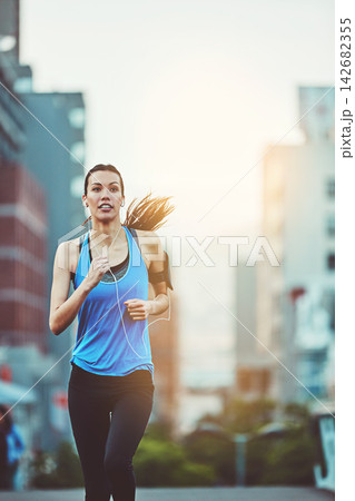 Woman, street and running for exercise with earphones, music streaming app and phone in morning. Girl, person or runner with audio, radio or listen on subscription in workout on road in San Francisco Woman, street and running for exercise with earphones, music streaming app and phone in morning. Girl, person or runner with audio, radio or listen on subscription in workout on road in San Francisco 142682355