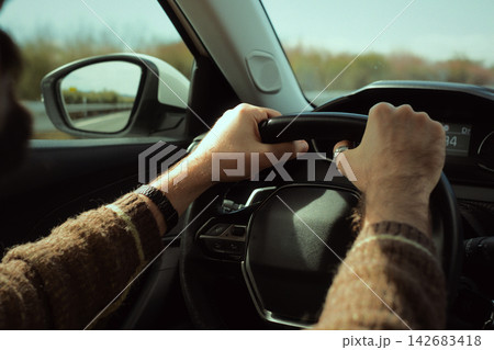 Man driving car on highway, hands gripping steering wheel, traveling and commuting with vehicle Man driving car on highway, hands gripping steering wheel, traveling and commuting with vehicle 142683418