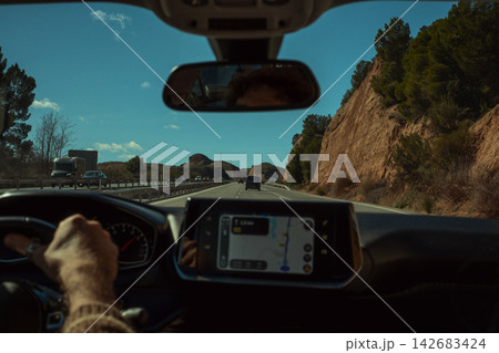 Person driving a car on an open road, navigating using the dashboard gps screen, enjoying a journey amidst rural scenery Person driving a car on an open road, navigating using the dashboard gps screen, enjoying a journey amidst rural scenery 142683424