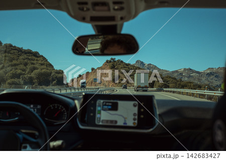 Car interior pov driving on mountain highway with truck traffic, navigating a road trip journey Car interior pov driving on mountain highway with truck traffic, navigating a road trip journey 142683427