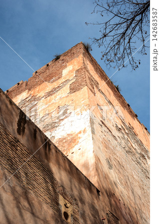 Ancient roman brick architecture with rough stucco texture under clear blue sky and bare tree branches Ancient roman brick architecture with rough stucco texture under clear blue sky and bare tree branches 142683587