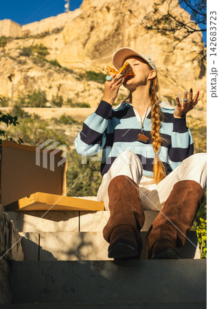 Young woman enjoying pizza outdoors on sunny day Young woman enjoying pizza outdoors on sunny day 142683723