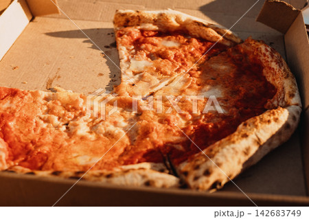 Half-eaten margherita pizza in a cardboard box at sunset 142683749
