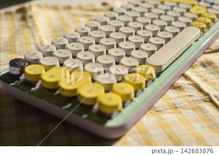 Retro keyboard on checkered fabric with yellow accents under sunlight Retro keyboard on checkered fabric with yellow accents under sunlight 142683876