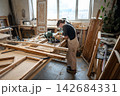 Craftswoman in woodworking workshop busy working on restoring vintage window frame at workbench. 142684331
