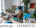 Woman applying colored epoxy resin to abstract artwork in home loft studio for small business. 142684332