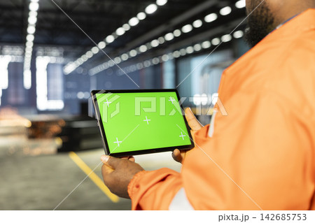 Mockup display tablet with black supervisor surrounded by metal tools in industrial facility, representing heavy industry labor and manufacturing power. Engineering workforce in factory. 142685753