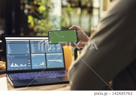 Isolated mockup on mobile phone screen used at home in kitchen, remote worker analyzing metrics and charts on laptop. Teleworking and outsourcing showing task management and research. Isolated mockup on mobile phone screen used at home in kitchen, remote worker analyzing metrics and charts on laptop. Teleworking and outsourcing showing task management and research. 142685762