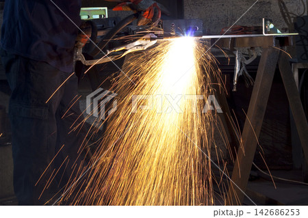 Industrial Welder Cutting Steel With Bright Sparks in Workshop 142686253