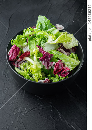 Fresh Mixed Green Salad in Black Bowl on Dark Textured Background Fresh Mixed Green Salad in Black Bowl on Dark Textured Background 142686256
