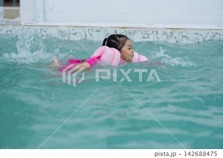 preschool child girl playing and swimming with floaties in pool water preschool child girl playing and swimming with floaties in pool water 142688475