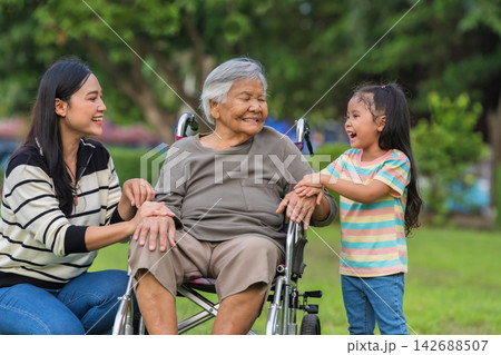 happy mother and daughter caring for grandmother in wheelchair at park 142688507