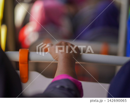 Close-up of a passenger's hand holding a handrail handle inside a public transport bus or train for balance during a daily city commute. 142690065