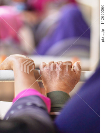 Close-up of a passenger's hand holding a handrail handle inside a public transport bus or train for balance during a daily city commute. 142690066