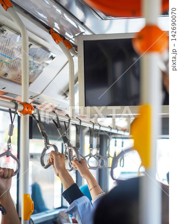 Close-up of a passenger's hand holding a handrail handle inside a public transport bus or train for balance during a daily city commute. 142690070