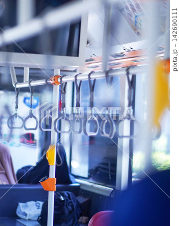 Row of hanging overhead handrail handles and grab straps inside a public transportation bus or train for passenger balance and safety. Row of hanging overhead handrail handles and grab straps inside a public transportation bus or train for passenger balance and safety. 142690111