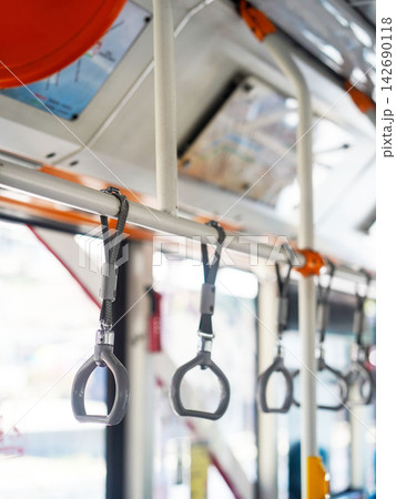 Row of hanging overhead handrail handles and grab straps inside a public transportation bus or train for passenger balance and safety. Row of hanging overhead handrail handles and grab straps inside a public transportation bus or train for passenger balance and safety. 142690118