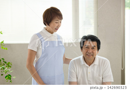 高齢者施設で働く60代の女性と利用者のシニアの男性 142690323