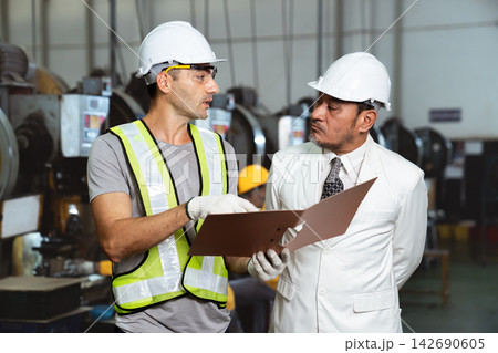 Asian factory manager discussing report with engineer in plant Asian factory manager discussing report with engineer in plant 142690605