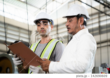 Asian factory manager discussing report with engineer in plant 142690609